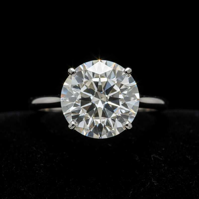 Grote ronde briljant-geslepen witte diamant in platina ring tegen donkere achtergrond